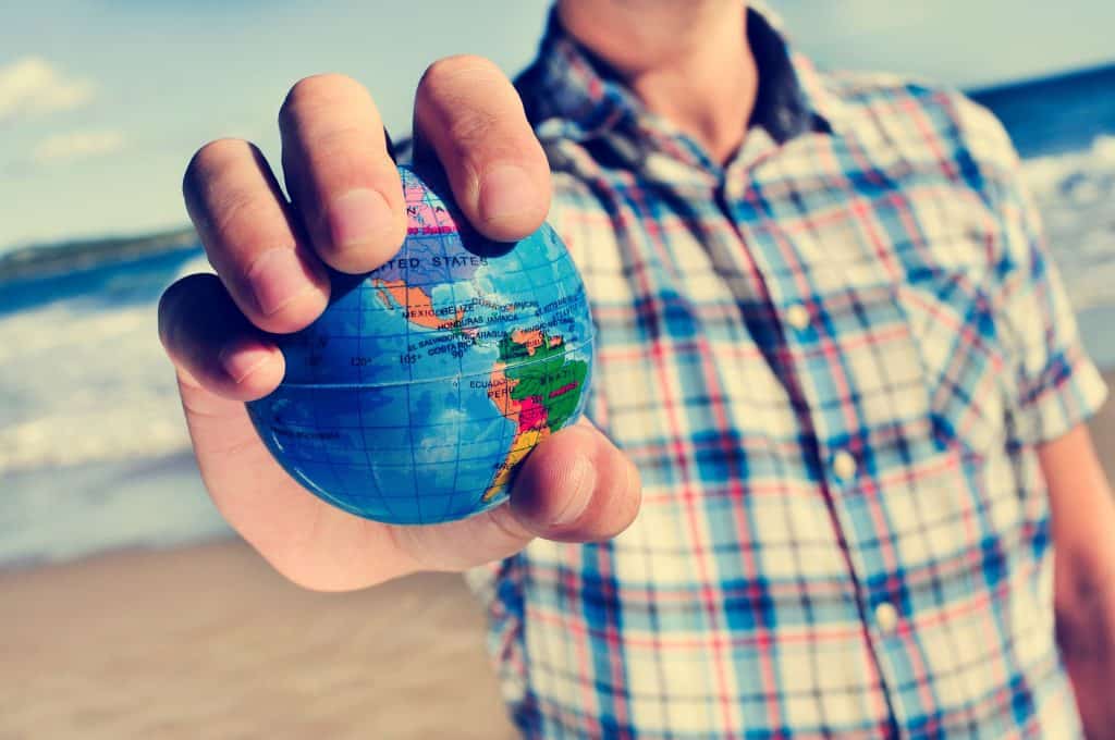 Man with a world globe in his hand showcasing starting an IVA if you live outside the UK