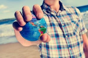 Man with a world globe in his hand showcasing starting an IVA if you live outside the UK