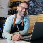 Can a self employed person do an IVA bakery owner working with laptop in a shop showcasing self employed IVA.