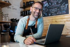 bakery owner working with laptop in a shop showcasing self employed IVA.