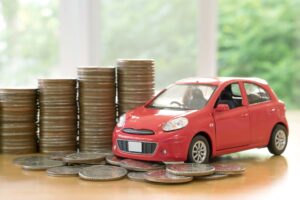 red car over a lot of stacked coins showcasing what happens to car finance in an IVA